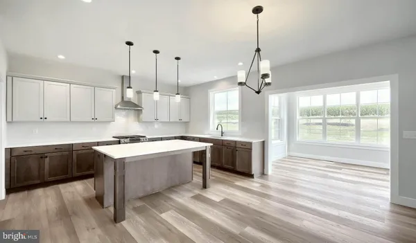 a large kitchen with granite countertop a stove a sink a center island and wooden floor