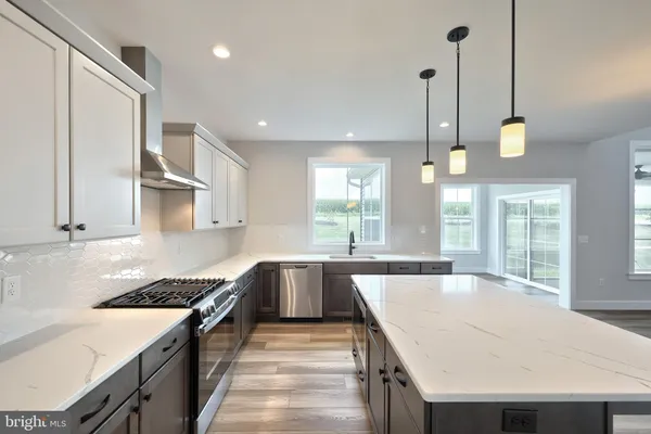 a kitchen with a stove a sink a counter top space and living room view