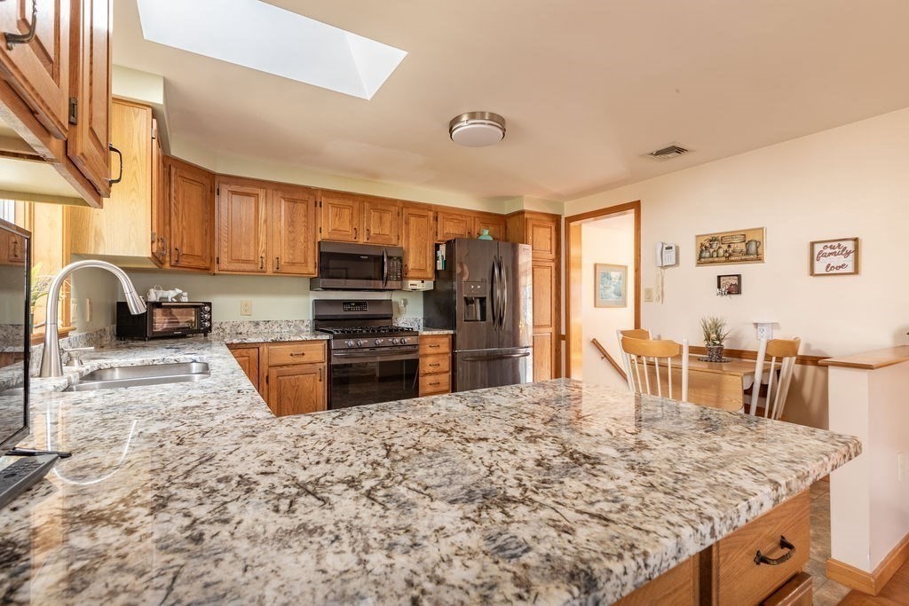 4 Clement Avenue Peabody, MA 01960 - Photo 8 of 25 a kitchen with stainless steel appliances kitchen island granite countertop a refrigerator a stove a sink a oven with a dining table and chairs