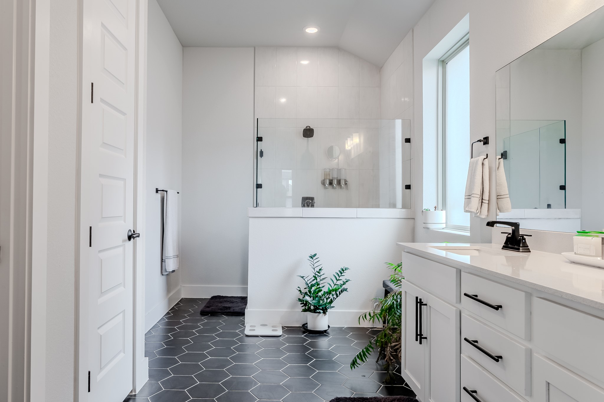 8109 Edmondson Bend Austin, TX 78744 - Photo 18 of 38 Modern bathroom featuring sleek hexagon tile flooring and a spacious walk-in shower with clear glass.