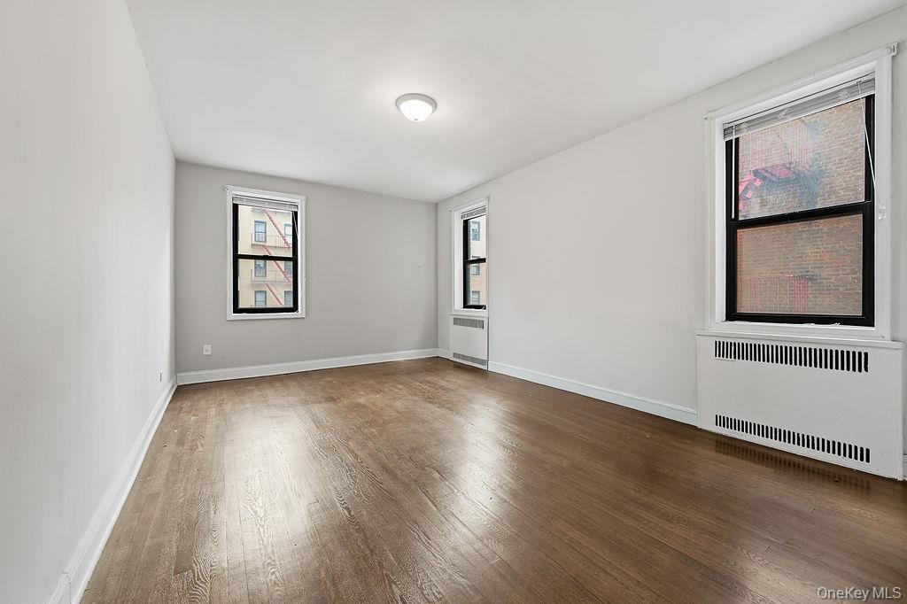 155-01 90th, Unit 3R Queens, NY 11432 - Photo 7 of 16 a view of an empty room with wooden floor and a window