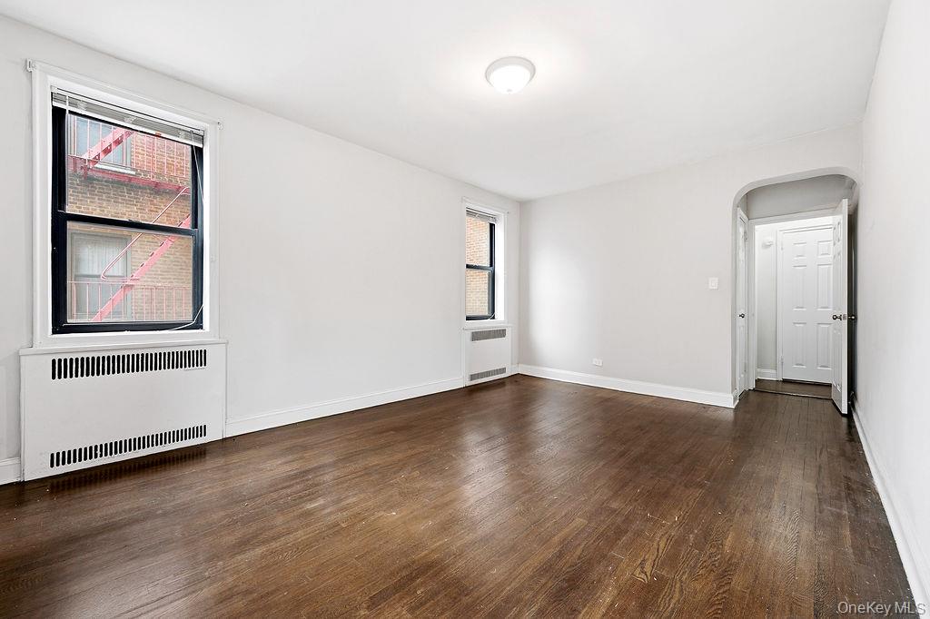 155-01 90th, Unit 3R Queens, NY 11432 - Photo 8 of 16 an empty room with wooden floor and windows
