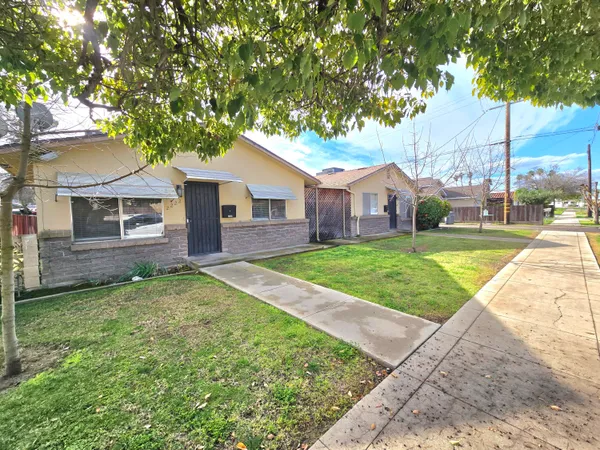 a view of a house with a yard and large tree