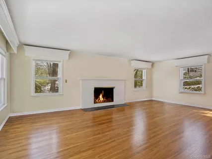 an empty room with wooden floor a fireplace and windows