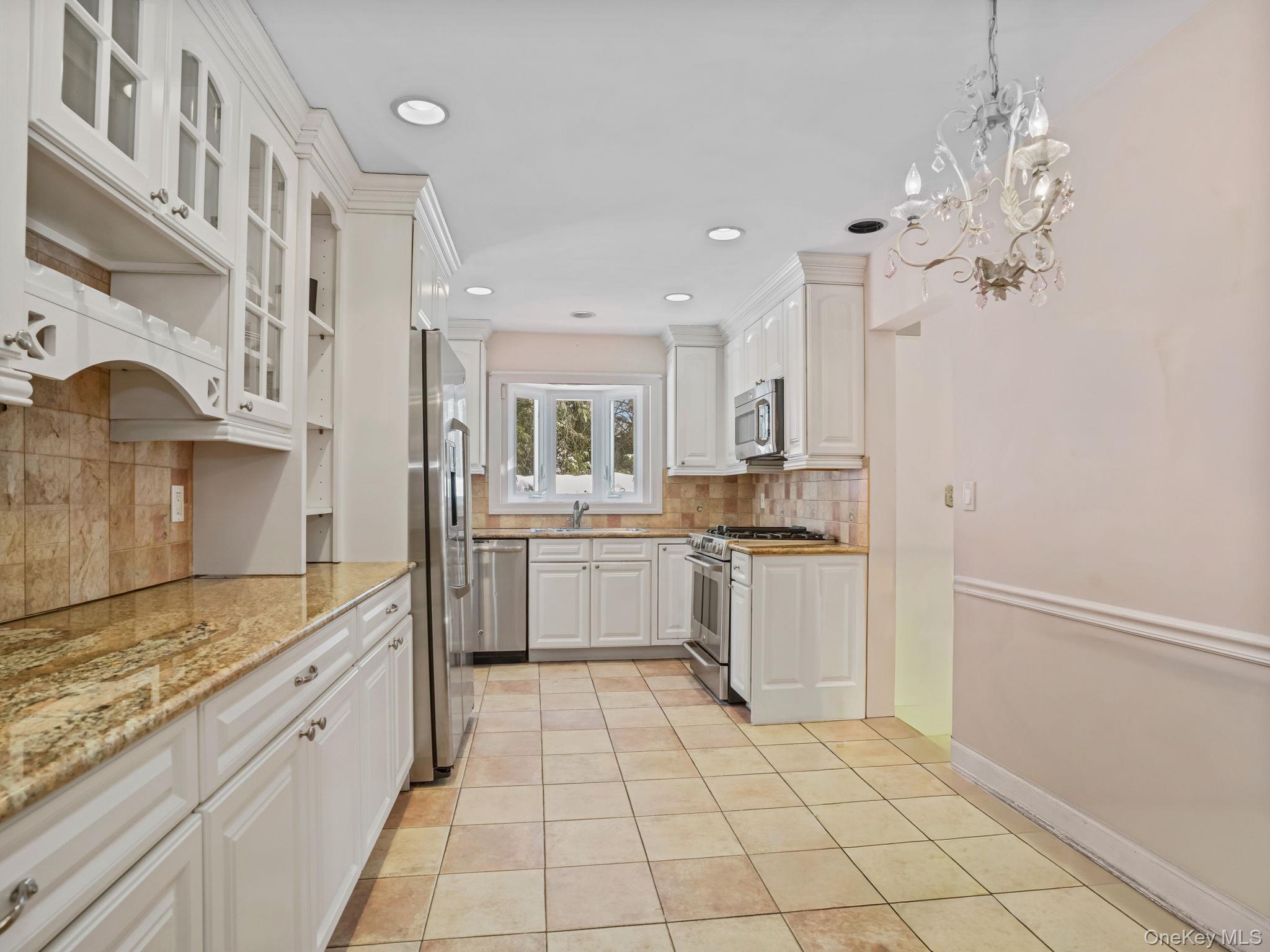 1 Village Lane Bronxville, NY 10708 - Photo 9 of 16 a large white kitchen with cabinets a island a stove a washer and dryer