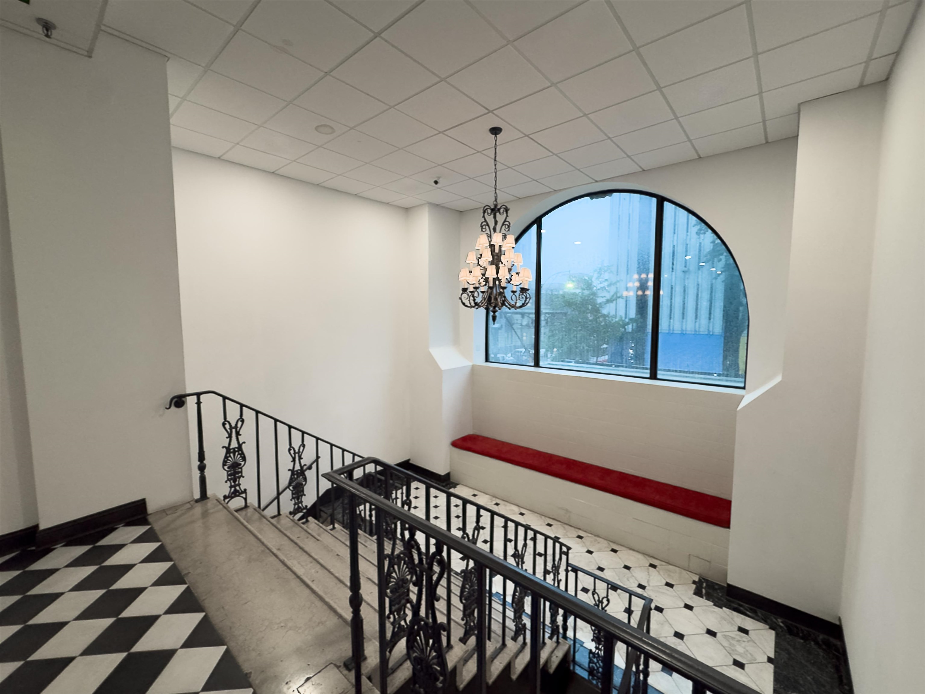 109 North Main Street, Unit 907 Memphis, TN 38103 - Photo 25 of 29 Grand staircase featuring a decorative wrought iron railing, arched window, and checkerboard floor tiling