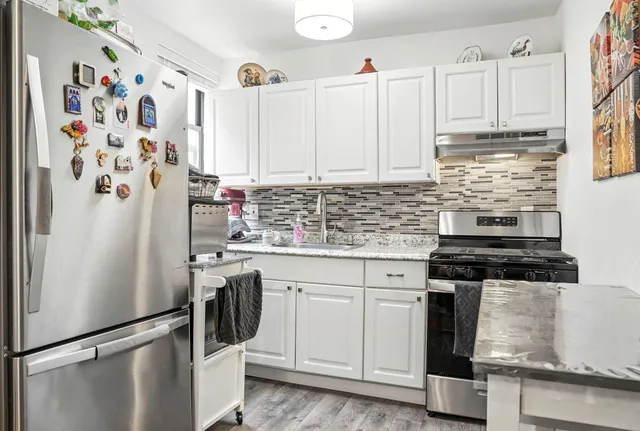 a kitchen with stainless steel appliances granite countertop a refrigerator sink stove and white cabinets