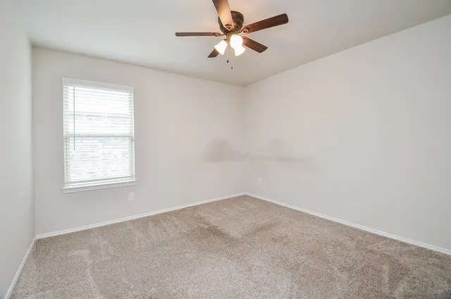 an empty room with a window and a fan