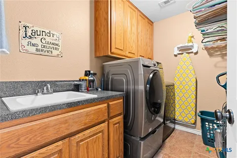 a bathroom with a granite countertop sink and a washing machine