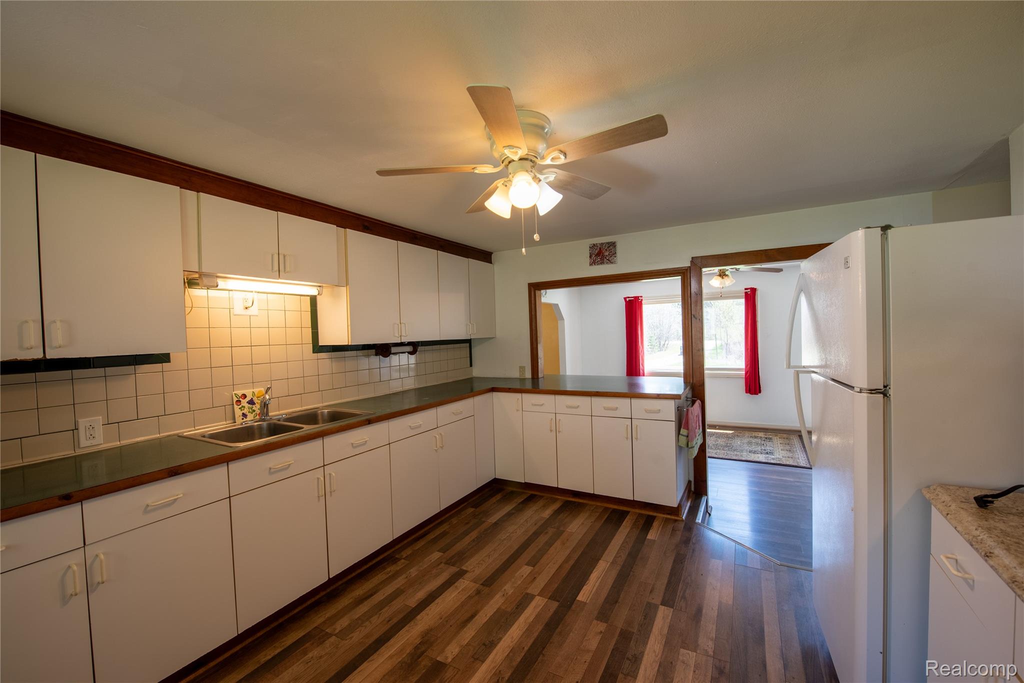 1190 Meadow Road Tawas City, MI 48763 - Photo 7 of 26 Kitchen with freestanding refrigerator, dark wood-style flooring, white cabinetry, and backsplash