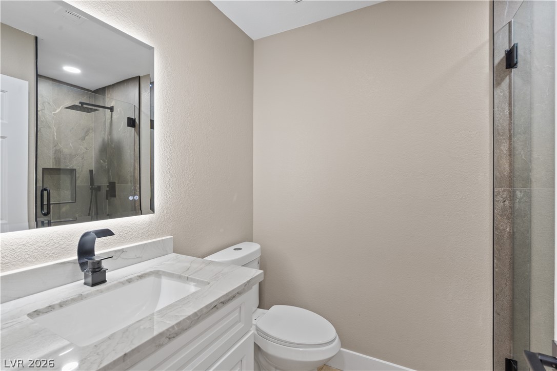1662 Ravanusa Drive Henderson, NV 89052 - Photo 27 of 74 A well-appointed bathroom features a sleek vanity with a modern faucet and a spacious, glass-enclosed shower.