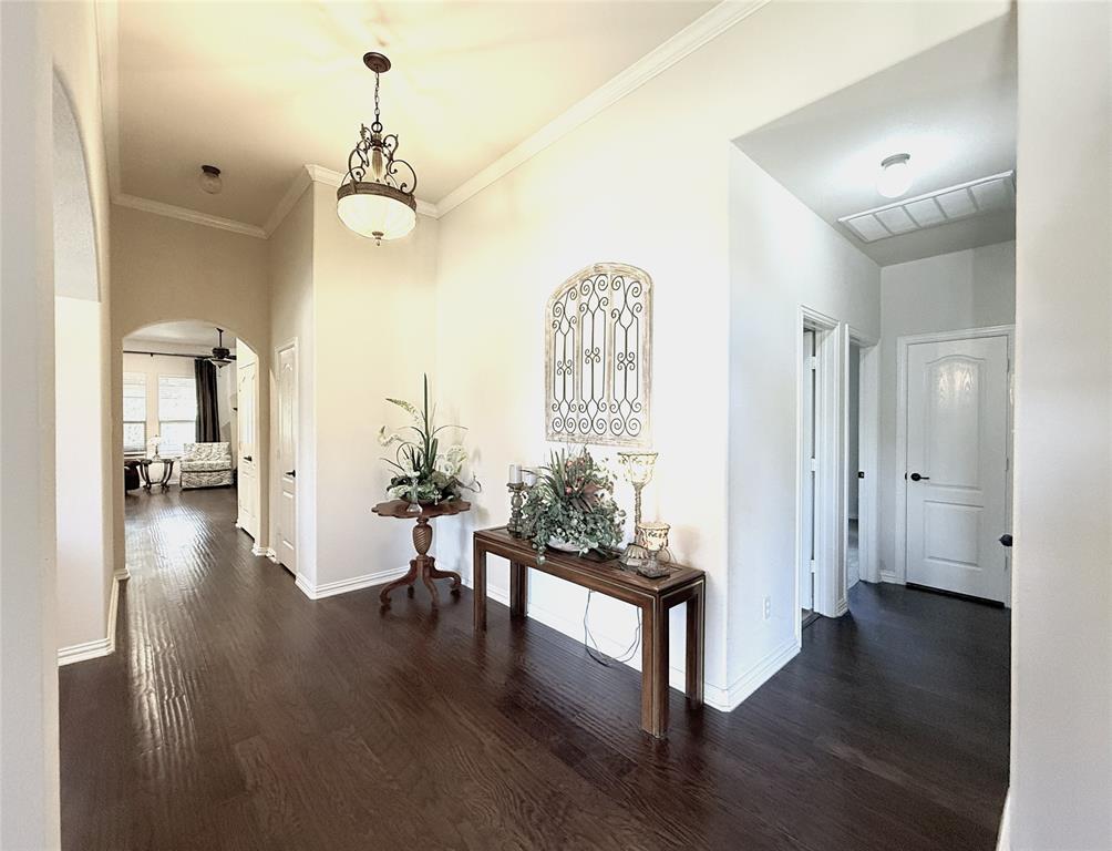 1301 Meadow Ranch Road McKinney, TX 75071 - Photo 11 of 40 Hallway featuring arched walkways, dark wood-type flooring, and crown molding