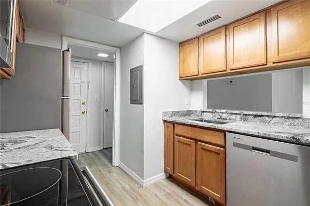 a kitchen with granite countertop cabinets stainless steel appliances a sink and a window