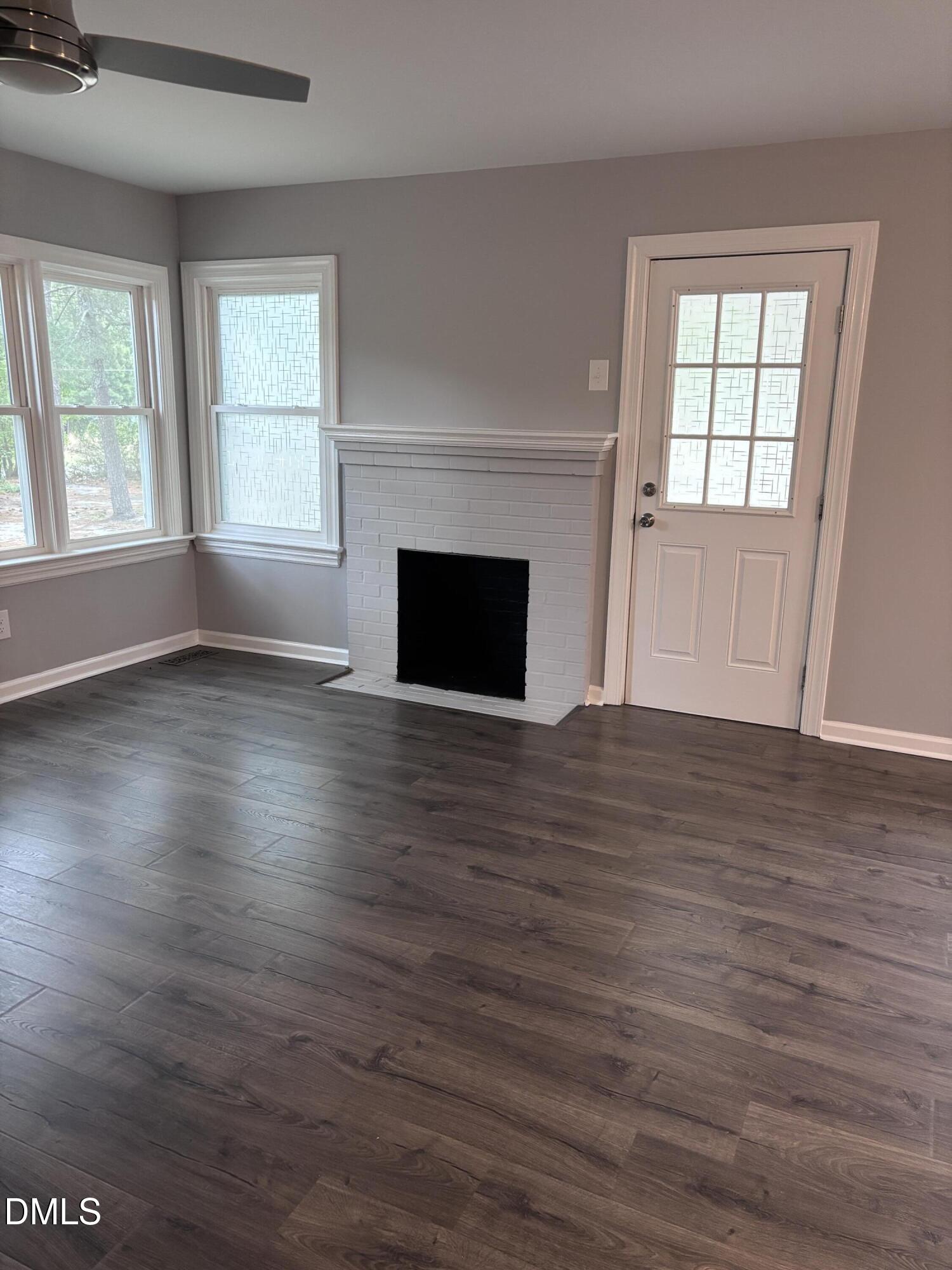 504 St Andrews Church Road Sanford, NC 27332 - Photo 5 of 22 an empty room with wooden floor fireplace and windows