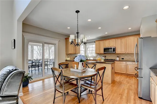 a kitchen with stainless steel appliances a dining table chairs and wooden floor
