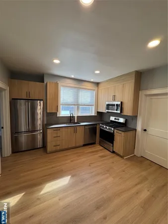 a kitchen with stainless steel appliances a refrigerator and a wooden floor