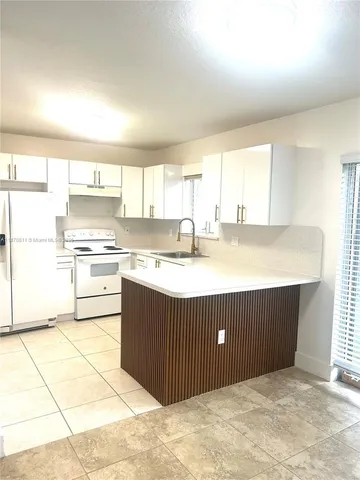 a kitchen with a cabinets a sink a stove a refrigerator and white cabinets