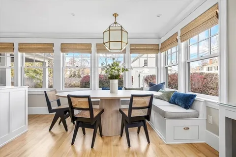 a dining room with wooden floor a chandelier a wooden table and chairs