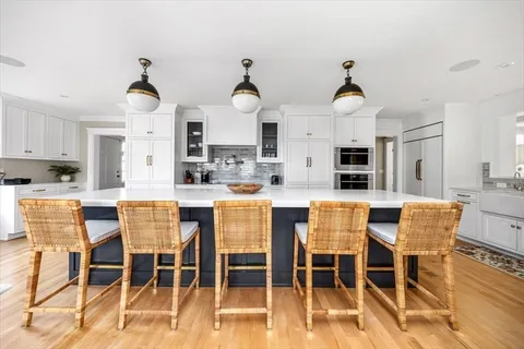 a kitchen with stainless steel appliances kitchen island granite countertop a dining table chairs and white cabinets