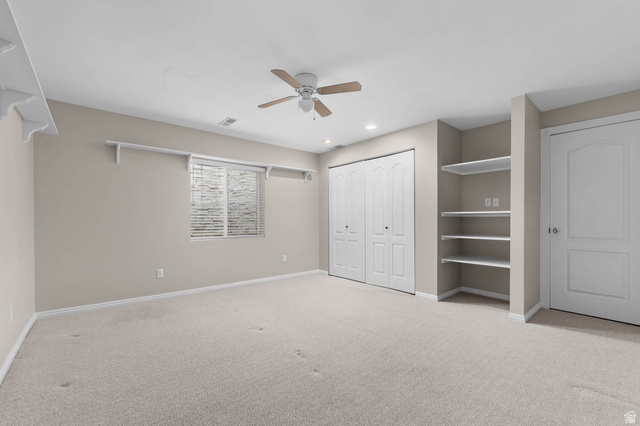 1417 Blacksmith Lane Draper, UT 84020 - Photo 31 of 57 Spacious room featuring neutral carpet flooring, a ceiling fan, a window with horizontal blinds, built-in shelving, and bi-fold closet doors