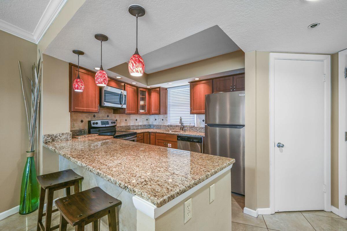 4252 Beachside 2, Unit 252 Miramar Beach, FL 32550 - Photo 7 of 27 a kitchen with stainless steel appliances granite countertop a sink refrigerator and microwave