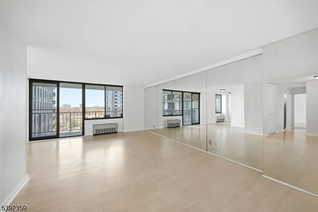 a view of an empty room with a window and wooden floor
