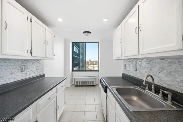 a kitchen with stainless steel appliances granite countertop a sink and white cabinets