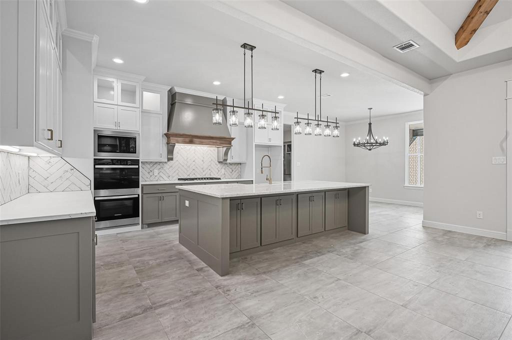 112 La Paloma Way Decatur, TX 76234 - Photo 11 of 37 Kitchen featuring decorative backsplash, a large island with sink, hanging light fixtures, light stone countertops, and recessed lighting