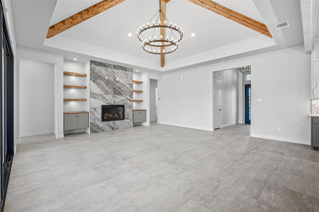 112 La Paloma Way Decatur, TX 76234 - Photo 9 of 37 Unfurnished living room featuring beam ceiling, a high end fireplace, a chandelier, a raised ceiling, and recessed lighting