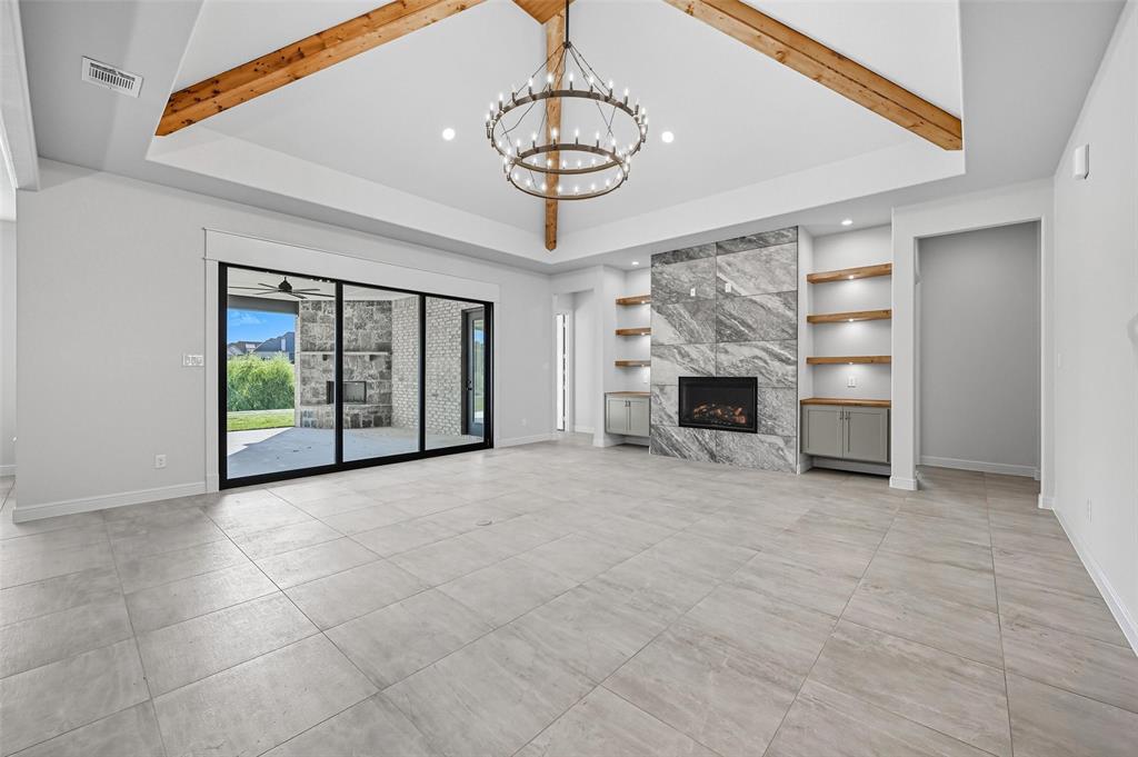 112 La Paloma Way Decatur, TX 76234 - Photo 10 of 37 Unfurnished living room with beamed ceiling, built in features, a fireplace, and a chandelier