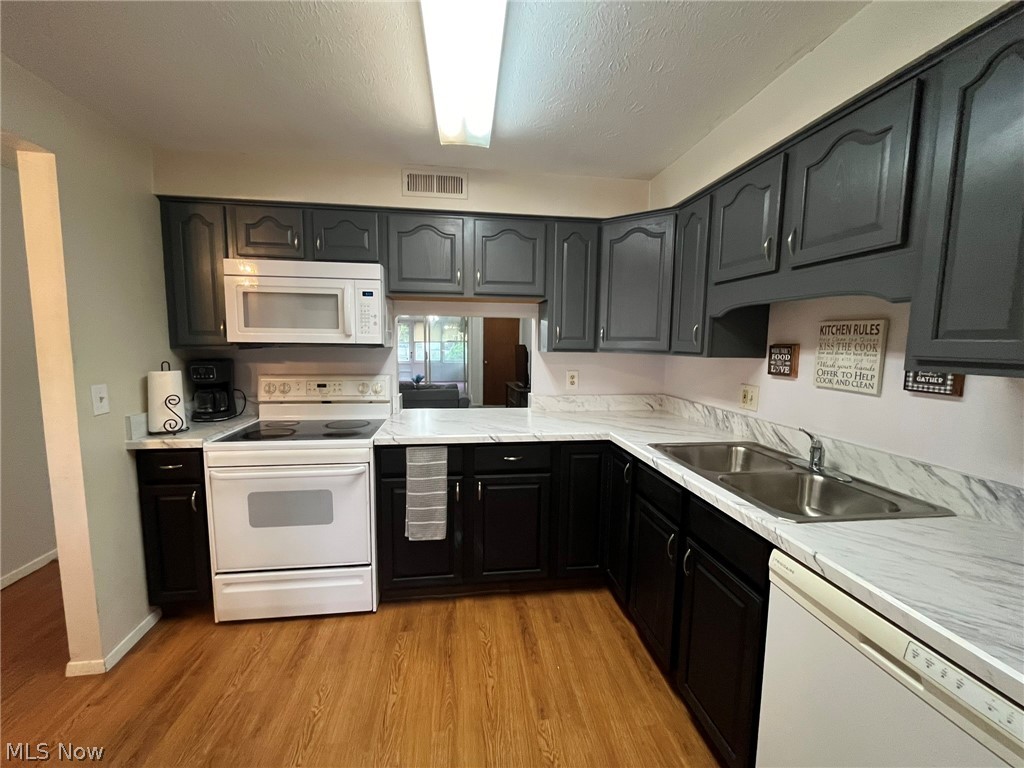 8945 West Ridge Road Elyria, OH 44035 - Photo 5 of 22 Kitchen with light wood-style floors, white appliances, sink, and a textured ceiling