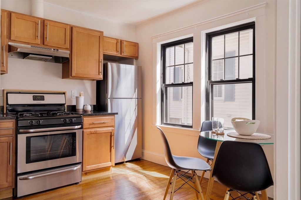 10 Washington Avenue, Unit 2 Waltham, MA 02453 - Photo 12 of 26 a kitchen with stainless steel appliances a stove a sink refrigerator and a table with chairs