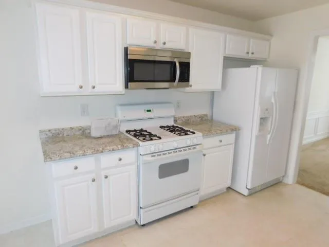 a kitchen with granite countertop white cabinets and refrigerator