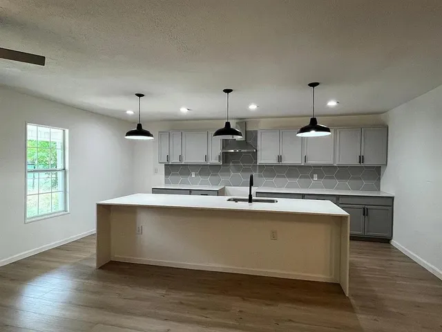 a large kitchen with stainless steel appliances granite countertop a sink stove and wooden floor