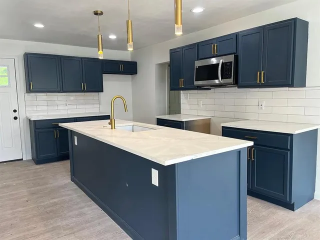 a kitchen with stainless steel appliances a sink a stove a microwave and wooden cabinets