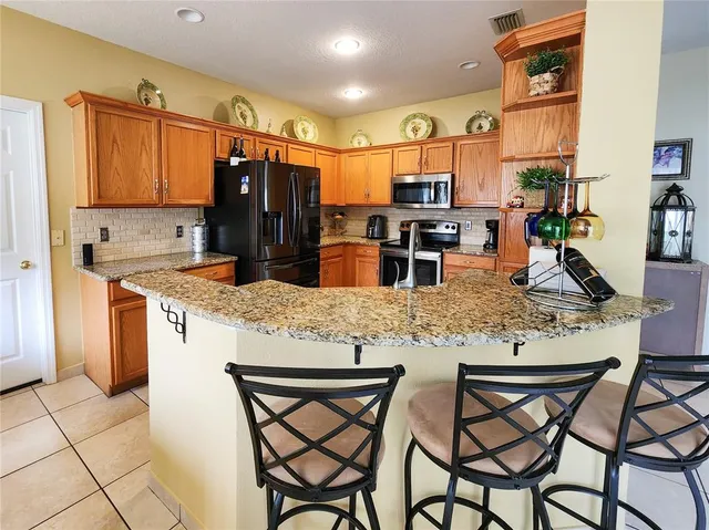 a kitchen with stainless steel appliances kitchen island granite countertop a table chairs and a refrigerator