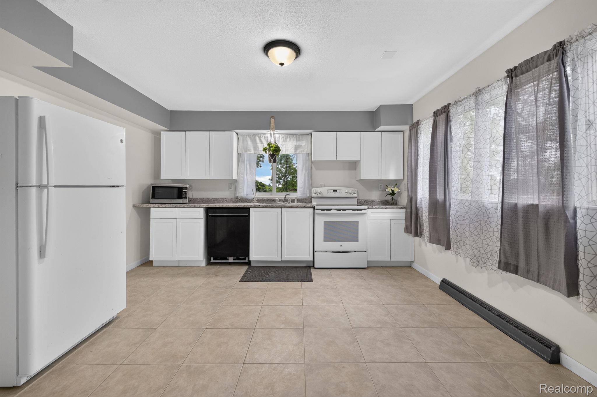 9288 Hilda Lane Flushing, MI 48433 - Photo 26 of 50 Bright kitchen featuring white cabinetry, light-colored tile flooring, white appliances, and a window over the sink
