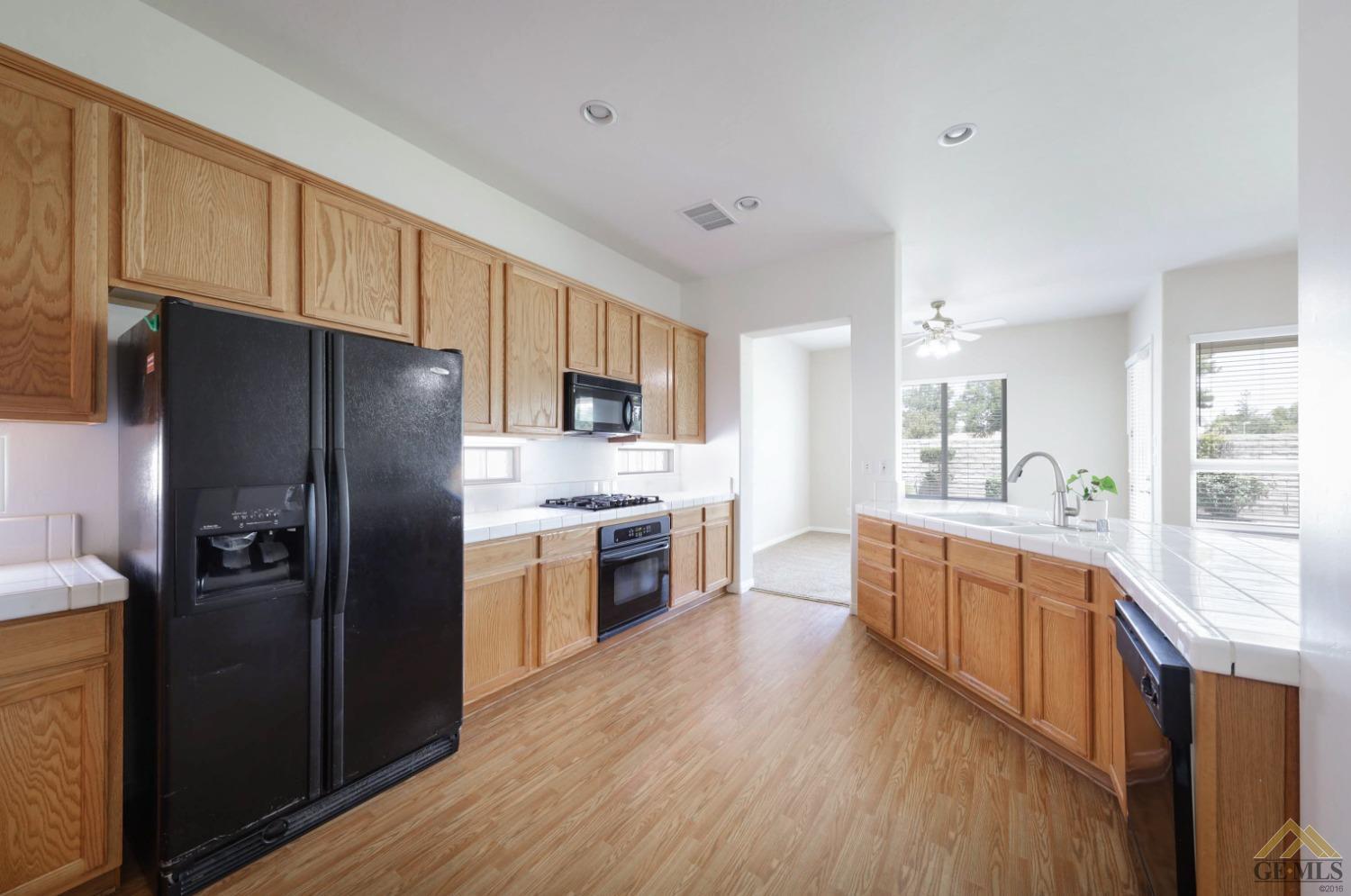 Undisclosed Address Bakersfield, CA 93311 - Photo 21 of 34 a large kitchen with cabinets wooden floor and stainless steel appliances