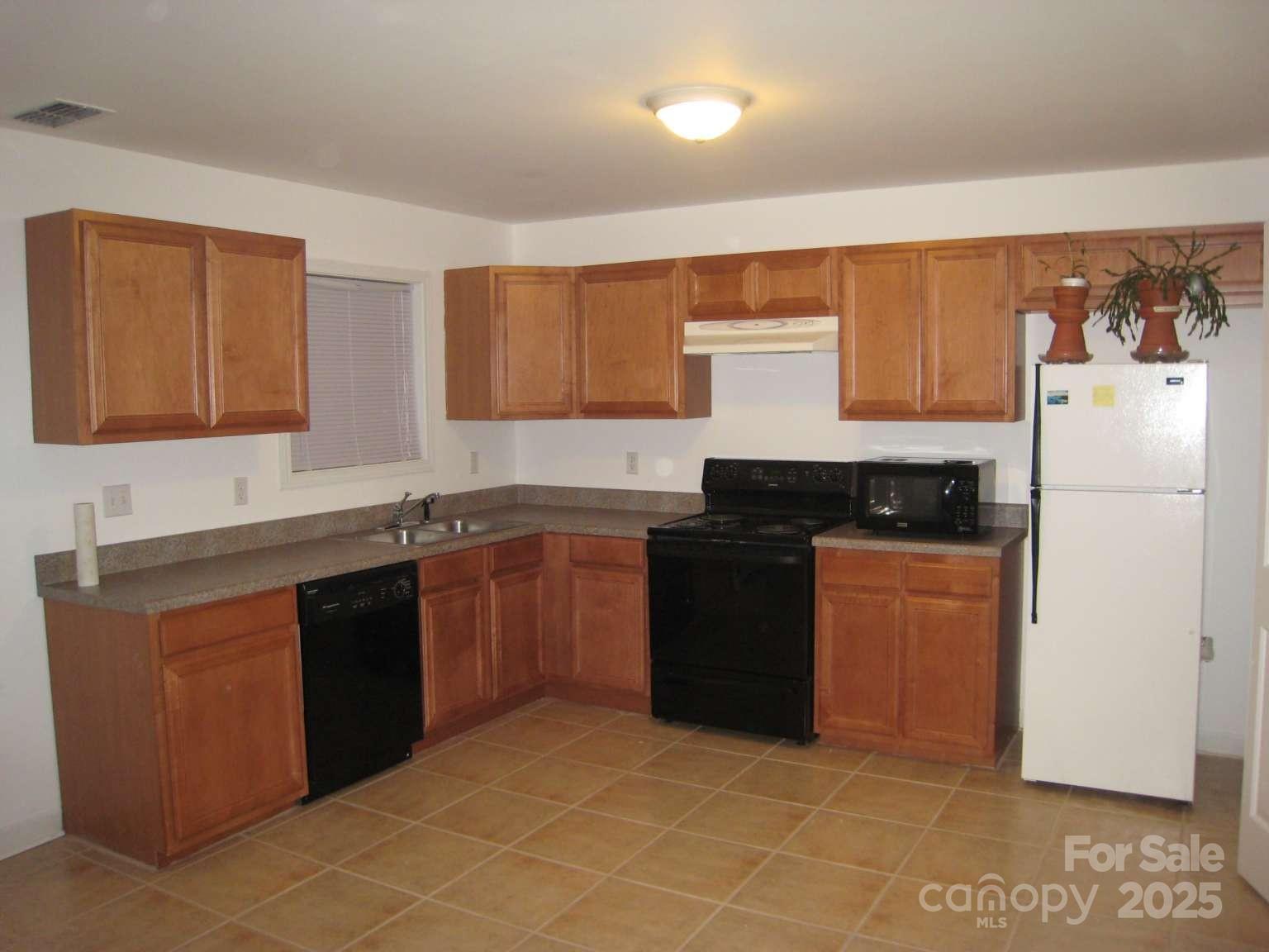 4653 Perkins Road Charlotte, NC 28269 - Photo 9 of 16 a kitchen with granite countertop a refrigerator and a sink