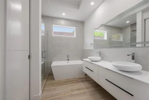 a bathroom with a double vanity sink mirror and bathtub