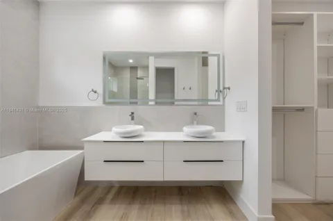 a bathroom with a sink double vanity granite tub and a mirror