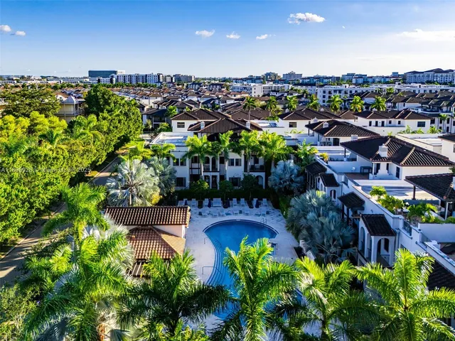 a view of a house with large windows and flower plants