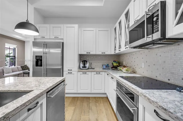 a living room with stainless steel appliances furniture a fireplace and a flat screen tv