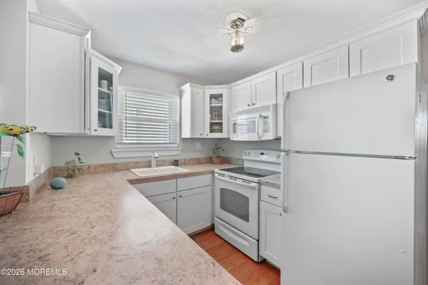 a kitchen with a sink a stove a refrigerator and white cabinets