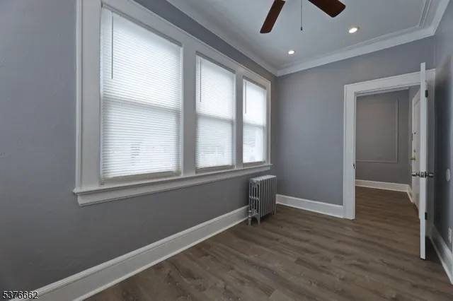 an empty room with wooden floor cabinet and windows