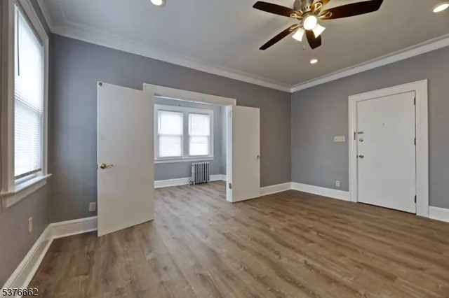 an empty room with wooden floor fan and windows
