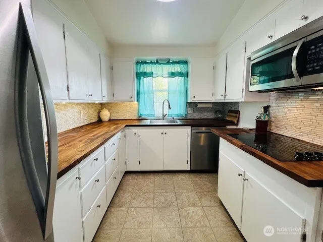 a kitchen with granite countertop white cabinets sink and stainless steel appliances