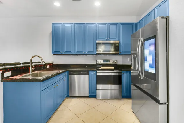a kitchen with kitchen island granite countertop a sink a stove and cabinets