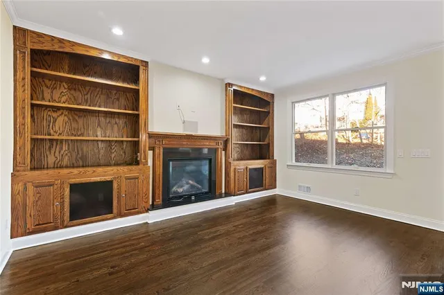 a view of an empty room with wooden floor fireplace and a window