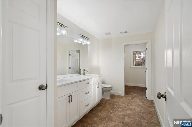a spacious bathroom with a toilet sink and mirror